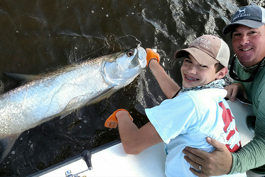 Boy releasing a tarpon beside the boat off the Georgia coast