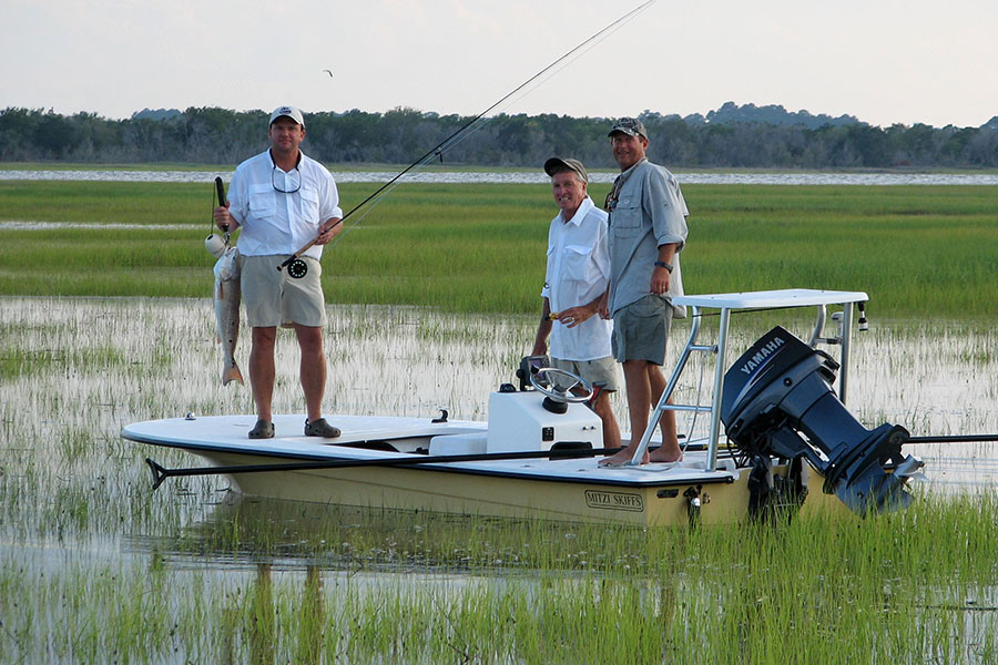 Anglers on a flats skiff in the spartina grass