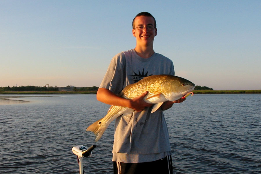 Teen angler holding a redfish at dawn