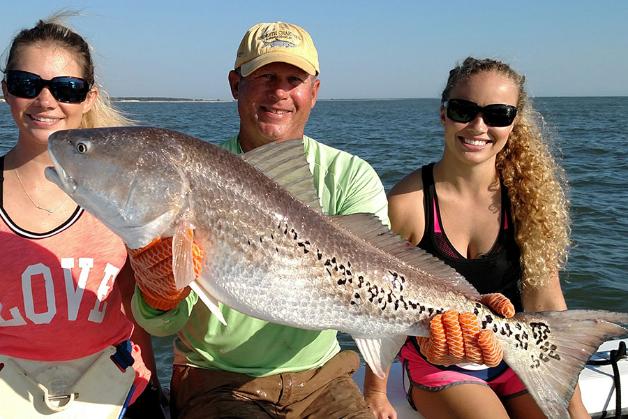 Family holding a big redfish on a Golden Isles fishing trip