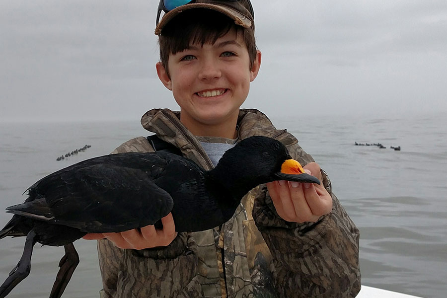 Young hunter holding a scoter duck