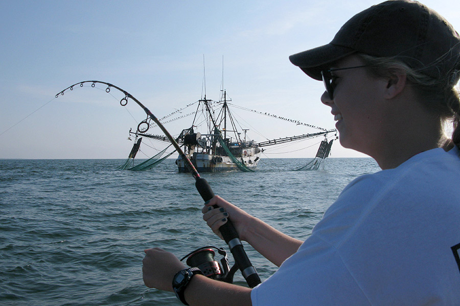 Angler fighting a fish near a shrimp boat off St. Simons Island