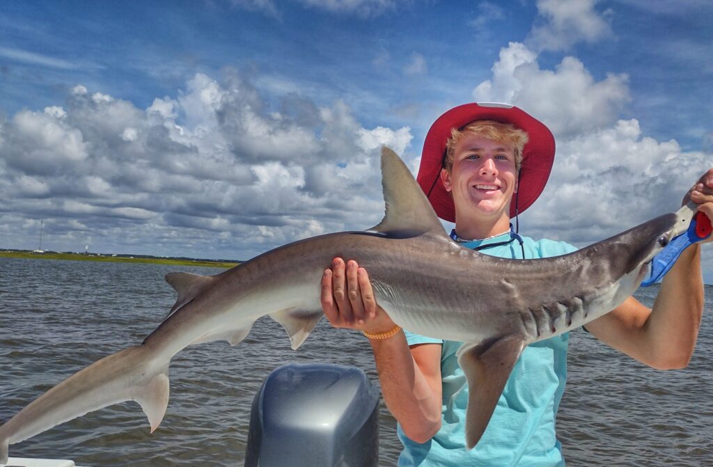 Young angler holding a shark on the boat