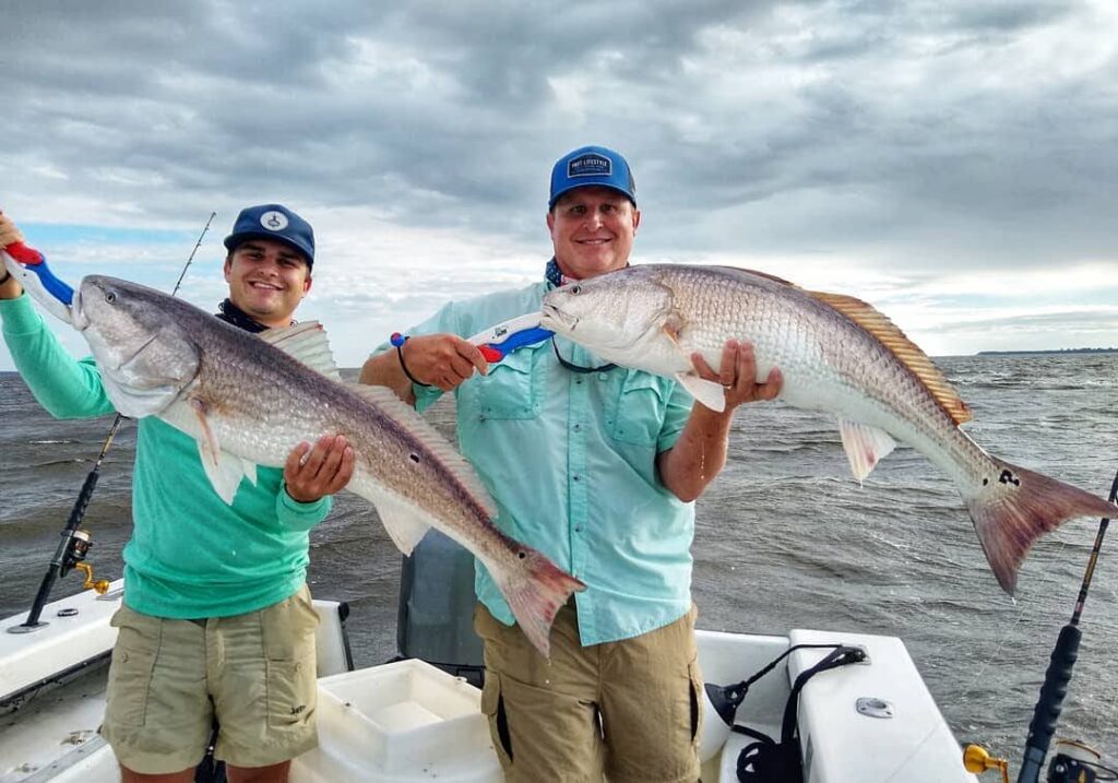 Two anglers holding bull redfish