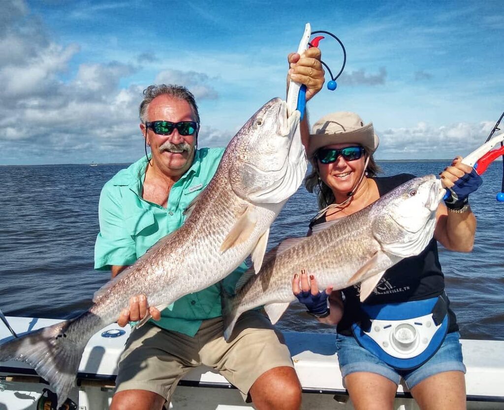 Two anglers showing their redfish catch