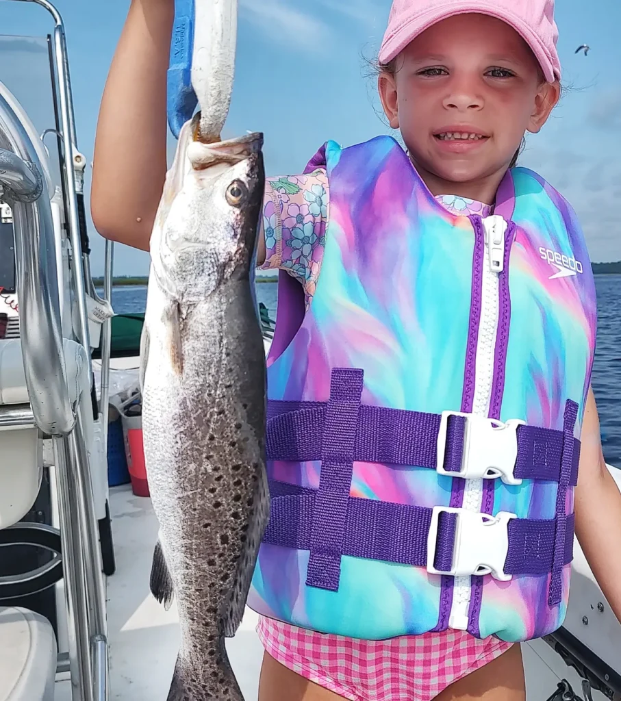 Young girl in a life jacket holding a seatrout