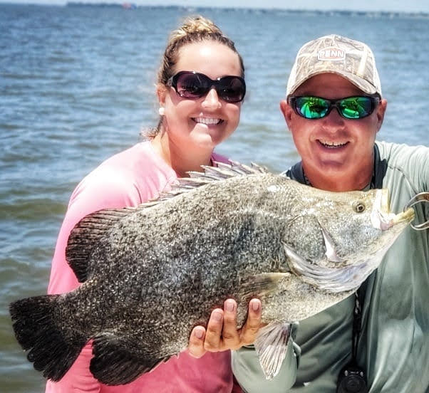 Couple holding a big tripletail